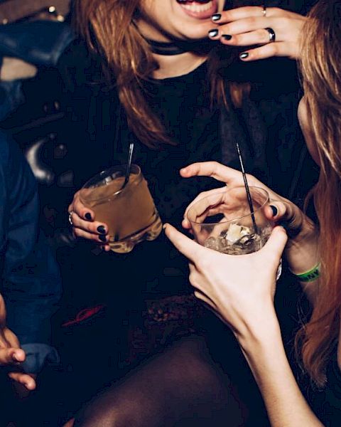 People are socializing and holding drinks, possibly at a party or club, enjoying their time together.