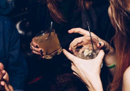 People are socializing and holding drinks, possibly at a party or club, enjoying their time together.