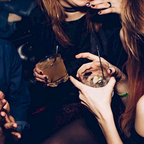 People are socializing and holding drinks, possibly at a party or club, enjoying their time together.