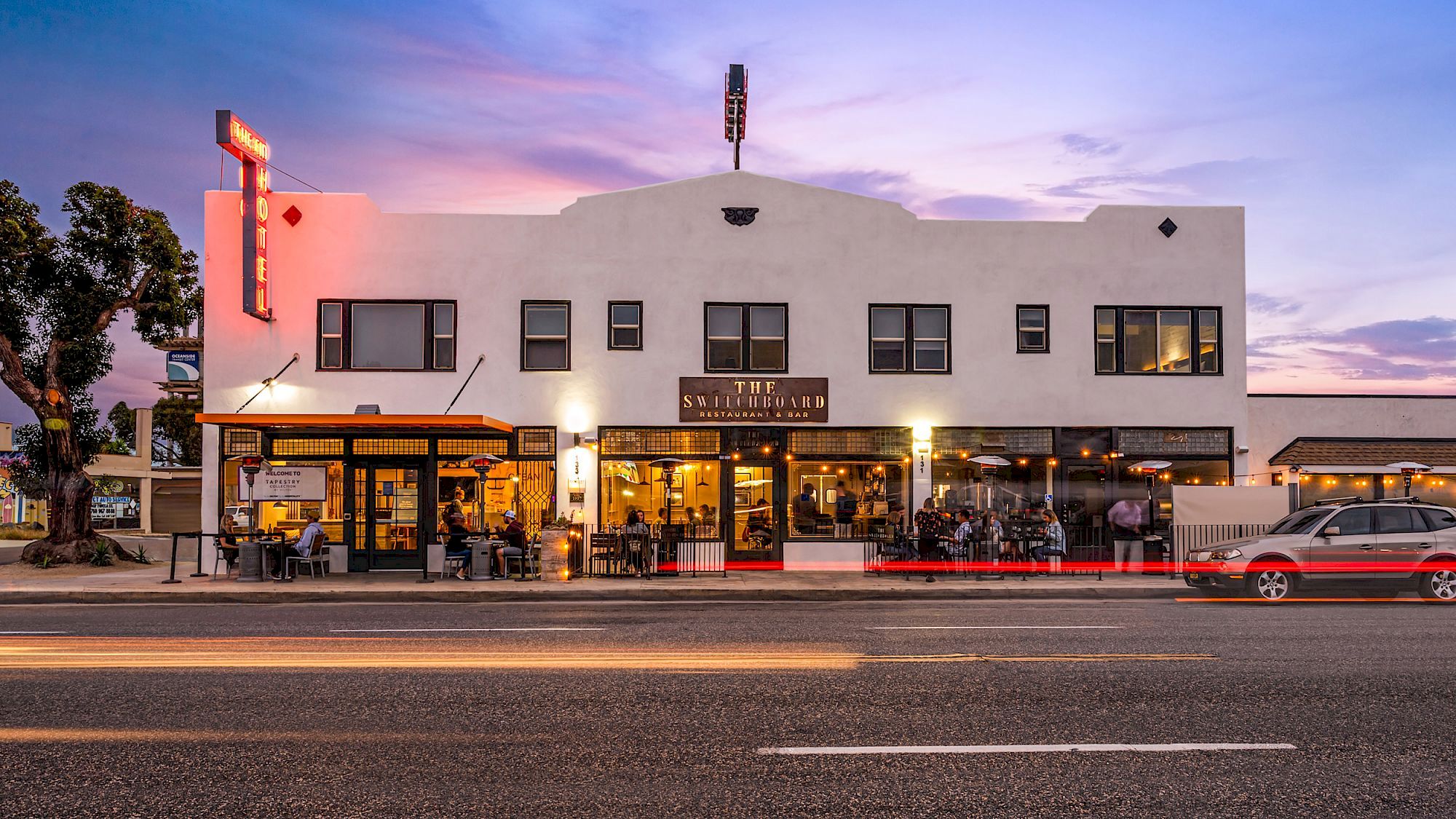 The image shows a street view of a restaurant with outdoor seating. The building has a retro design and the name 